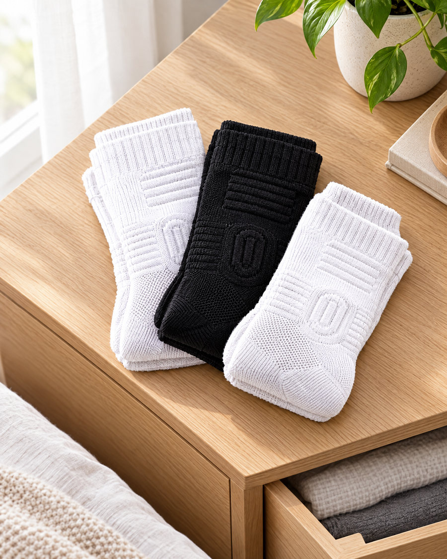 Three pairs of cushioned compression socks folded on a dresser